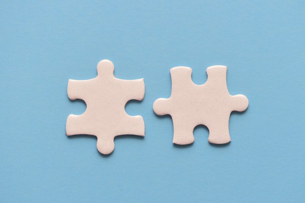 Das Bild zweigt zwei weiße Puzzleteile auf hellblauem Untergrund. Die Puzzleteile sind nicht verbunden, liegen aber nah beieinander. Das Bild symbolisiert die methodische Praxis, in Umfragen komplexe Sachverhalte auf mehrere Fragen aufzutrennen.