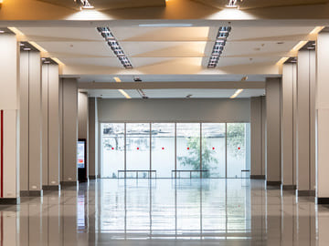 Leere Halle mit hoher Decke, vielen Säulen und einer Spiegeltür in der Mitte. Diese Stimmung und dieser Tonfall sind typisch für das moderne Design des Innenraums.