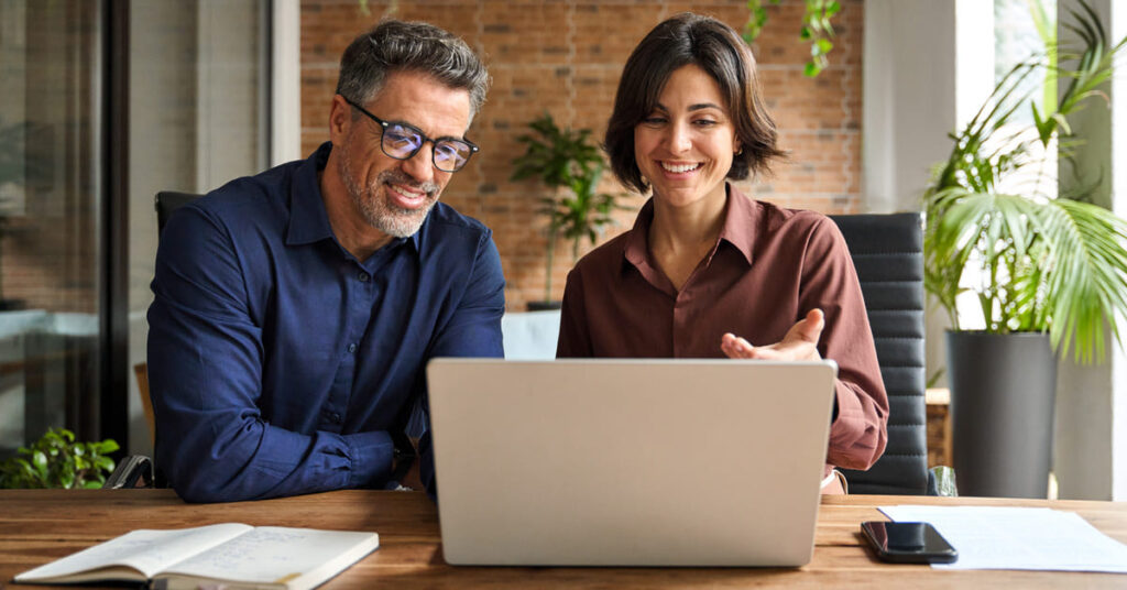 Coverbild der Studie zur HR-Digitalisierung: Zwei lächelnde Mitarbeiter sitzen gemeinsam an einem Laptop in einem modernen Büro – symbolisiert die digitale Transformation im Personalwesen des Mittelstands.
